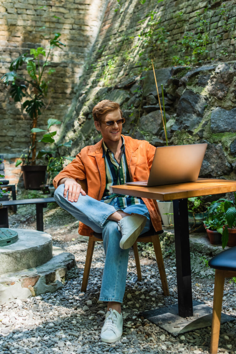 Junger Mann arbeitet mit Laptop in einem Café im Freien – flexible Arbeitsumgebung bei einer Workation.